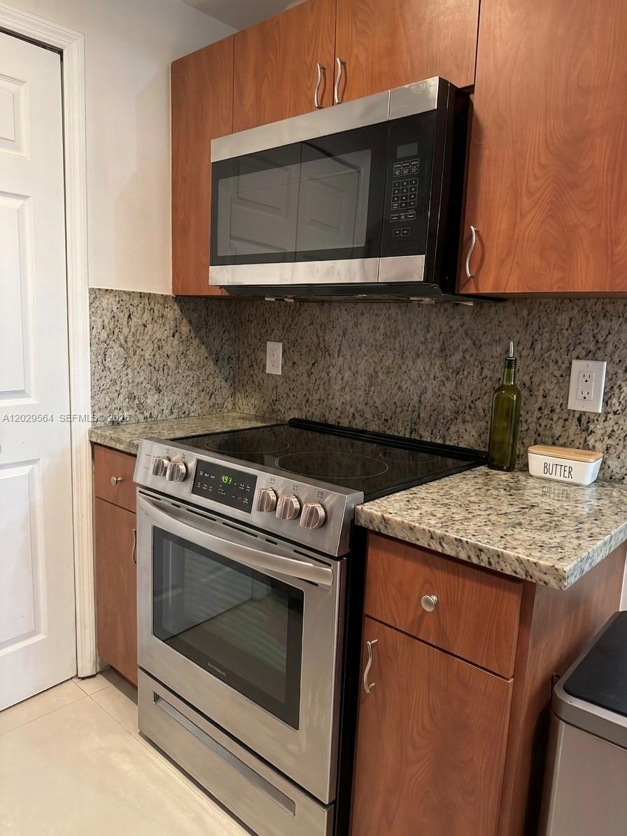 A kitchen features wood cabinets, granite countertops, and stainless steel appliances — 6540 NW 114th Ave # 1408, Doral FL 33178, DORAL, FL