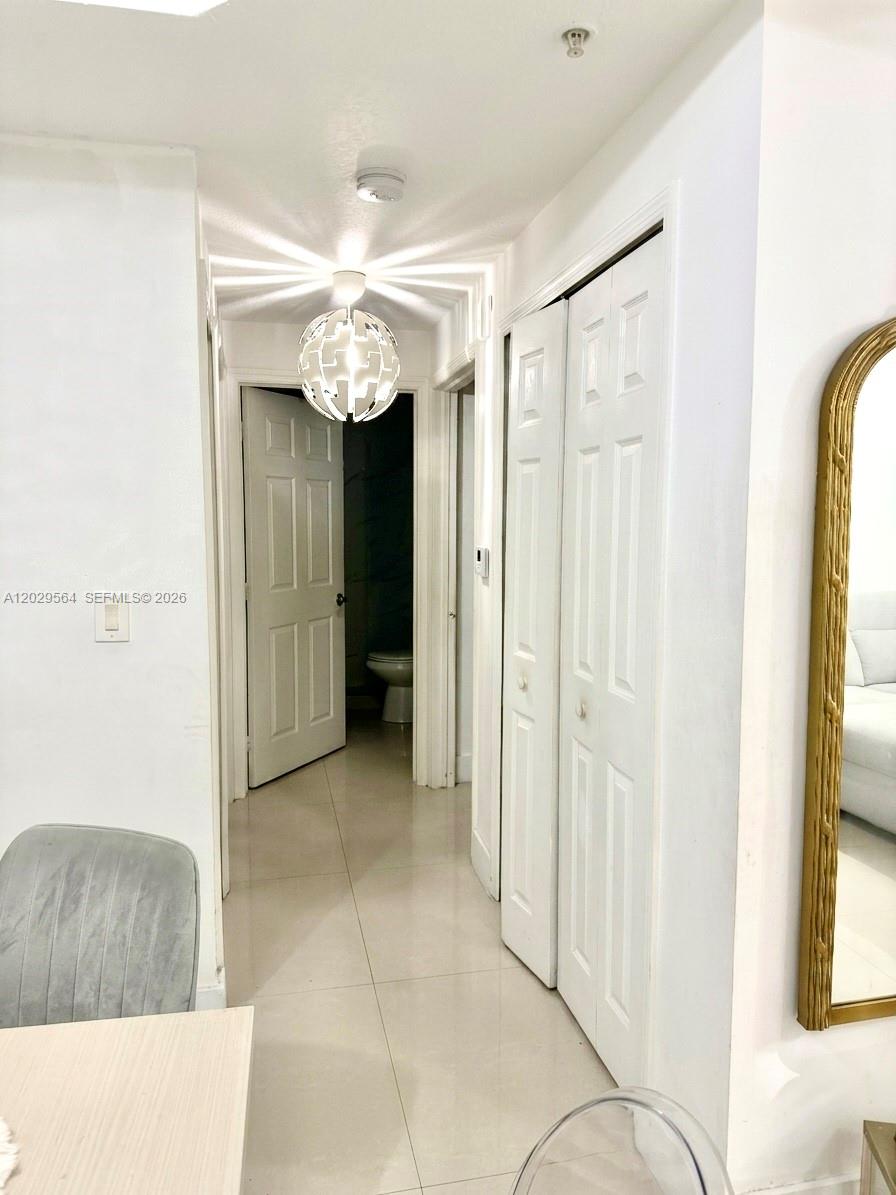 A hallway features white doors, a modern pendant light, and light-colored tile flooring — 6540 NW 114th Ave # 1408, Doral FL 33178, DORAL, FL