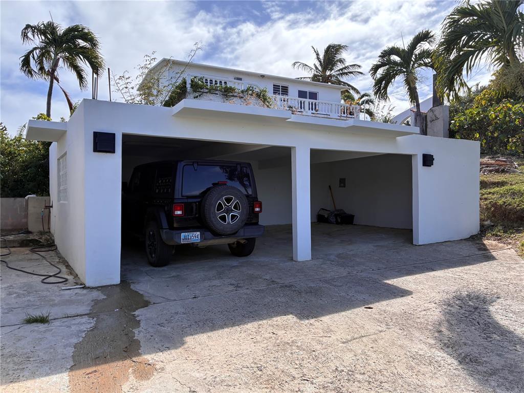 A white two-car carport with a black Jeep parked inside sits below a house — 397 CASA EGRETTA, VIEQUES, PR