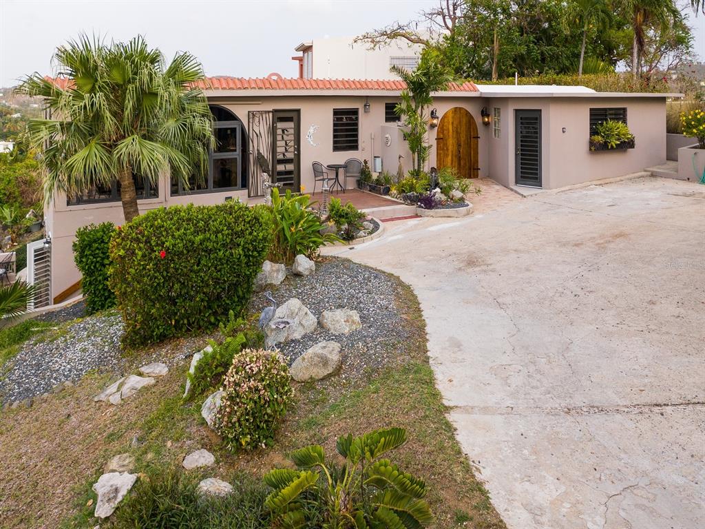 A single-story house with a concrete driveway, landscaped yard, and arched wooden front door — 397 CASA EGRETTA, VIEQUES, PR
