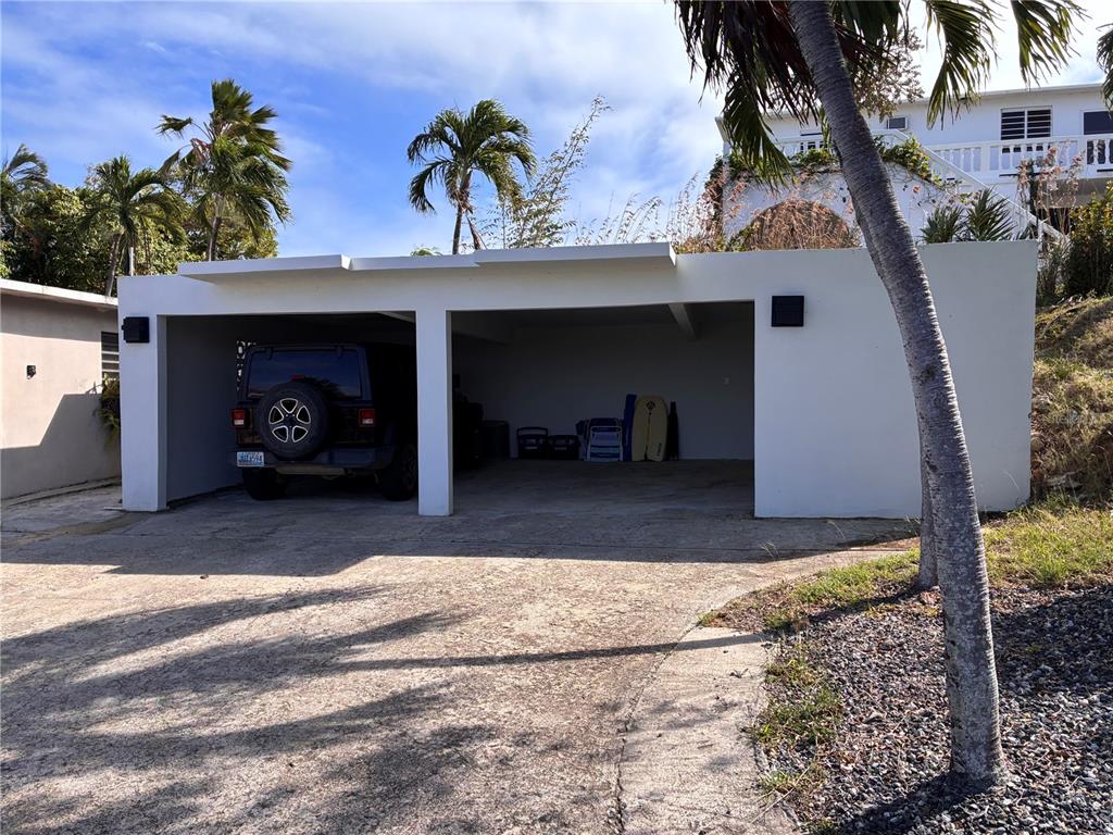 A two-car concrete carport sits in front of a house with palm trees nearby — 397 CASA EGRETTA, VIEQUES, PR