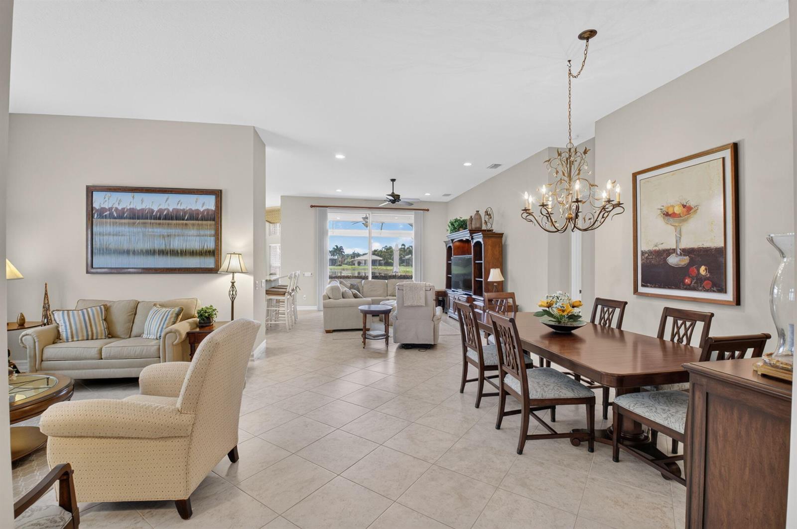 An open-concept living and dining area features tile flooring, a chandelier, and a rear view — 10830 Leaf Bridge Way, Boynton Beach FL 33473, BOYNTON BEACH, FL