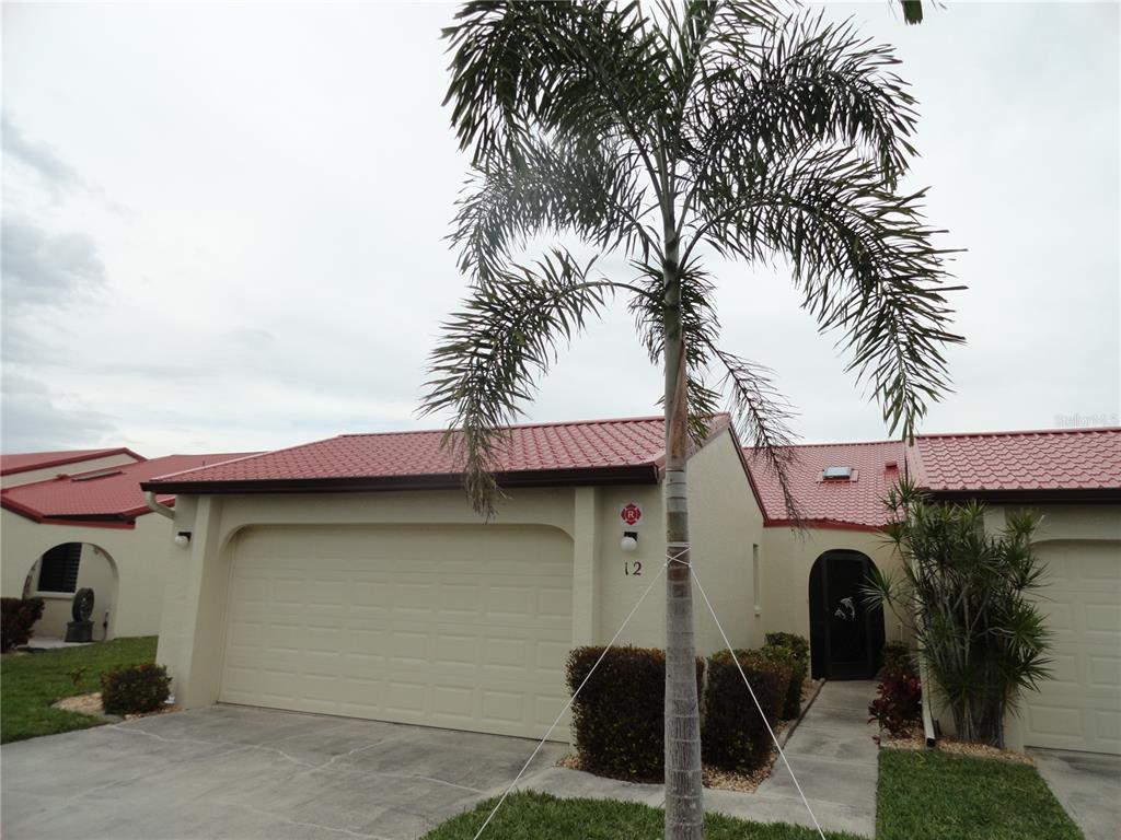 A single-story house with a red tile roof, a garage, and a palm tree — 3830 BAL HARBOR BOULEVARD UNIT 12, PUNTA GORDA, FL