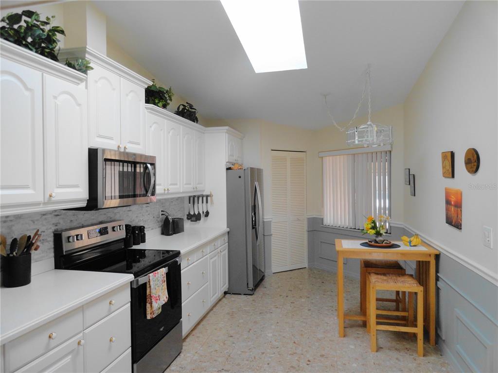 A kitchen with white cabinets, stainless steel appliances, a skylight, and a small dining table — 3830 BAL HARBOR BOULEVARD UNIT 12, PUNTA GORDA, FL