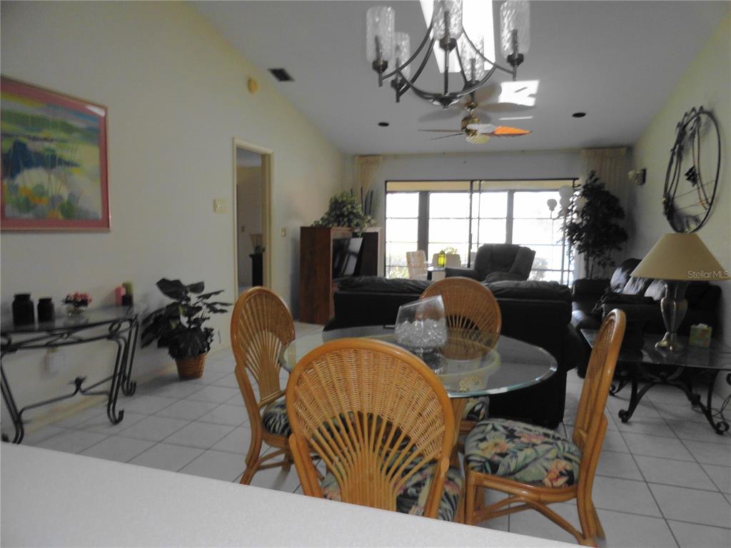 A dining area with a glass table and wicker chairs sits before a living room — 3830 BAL HARBOR BOULEVARD UNIT 12, PUNTA GORDA, FL
