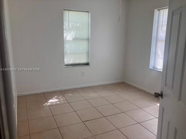 An empty bedroom features white walls, tan tile flooring, and two windows with blinds — 3698 William Ave # 6, Miami FL 33133, MIAMI, FL