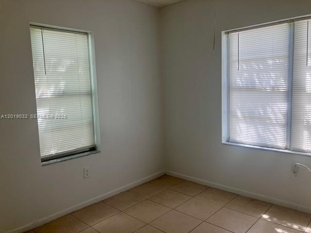 An empty room features white walls, beige tile flooring, and two windows with closed blinds — 3698 William Ave # 6, Miami FL 33133, MIAMI, FL