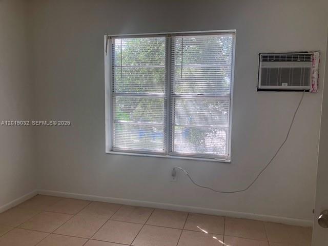 A room with light-colored tile flooring, a window with blinds, and a wall-mounted air conditioner — 3698 William Ave # 6, Miami FL 33133, MIAMI, FL