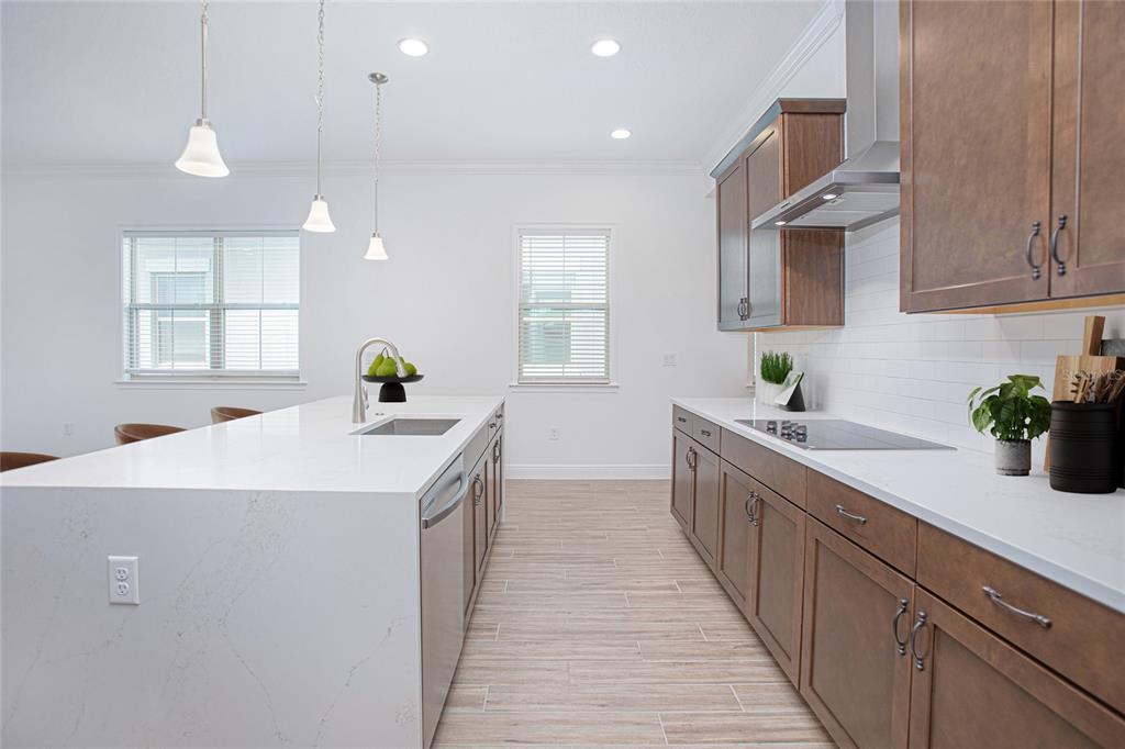 A modern kitchen features a white quartz island, wood cabinets, and light-colored tile flooring — 13300 BROMBOROUGH DRIVE, ORLANDO, FL