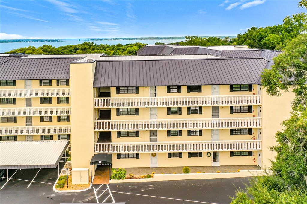 An exterior view of a multi-story apartment building with balconies overlooking a body of water — 101 N GRANDVIEW STREET, MOUNT DORA, FL