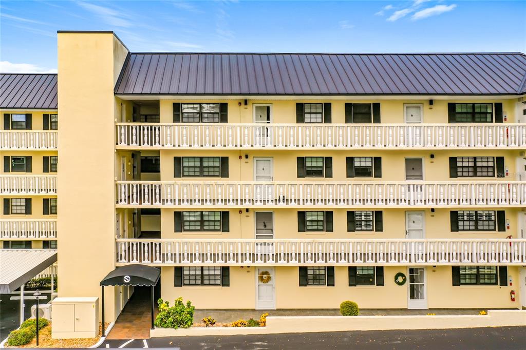 A three-story yellow apartment building features white railings, black shutters, and a dark metal roof — 101 N GRANDVIEW STREET, MOUNT DORA, FL