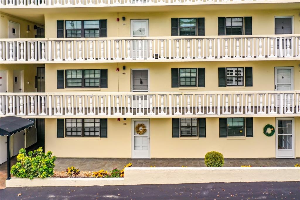 A three-story apartment building exterior features yellow walls, white railings, and multiple entry doors — 101 N GRANDVIEW STREET, MOUNT DORA, FL