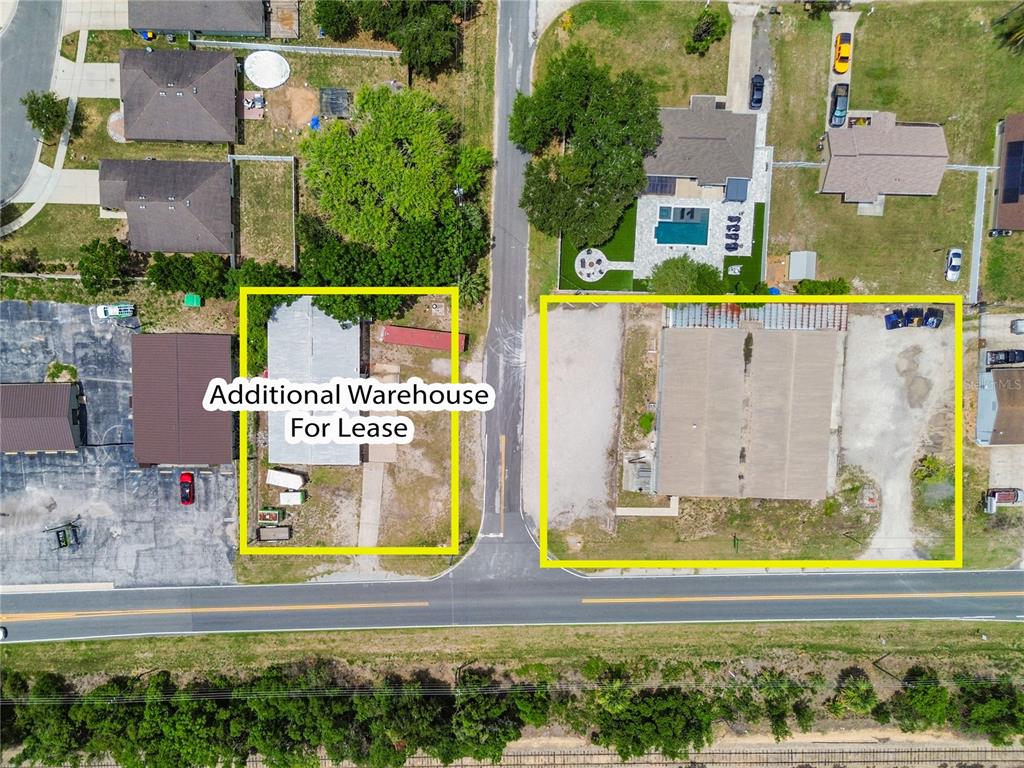This aerial view shows two commercial properties with warehouses and parking lots along a road — 15617 OLD US HIGHWAY 441, TAVARES, FL