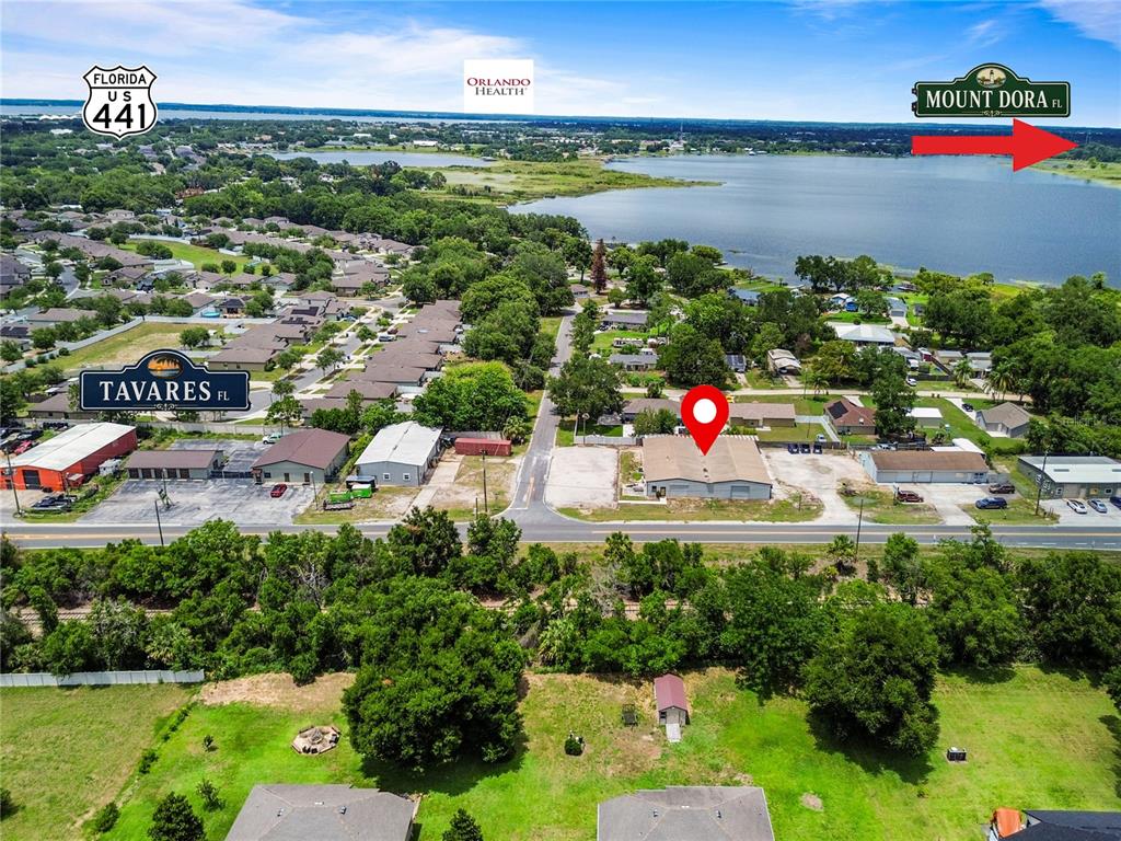 This aerial view shows a commercial building with a red location pin near a lake — 15617 OLD US HIGHWAY 441, TAVARES, FL