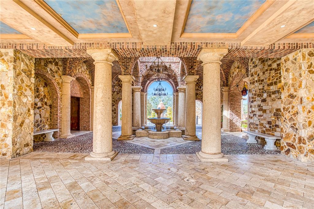 An outdoor stone patio features arched brick ceilings, classical columns, and a central tiered fountain — 16217 PENDIO DRIVE, MONTVERDE, FL
