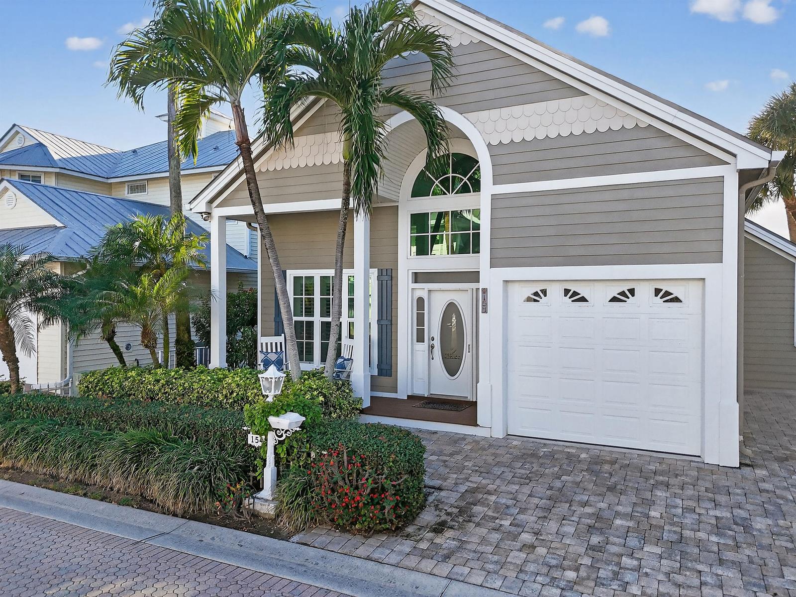 A gray house with a white garage door, arched window, and palm trees in front — 154 Jupiter Key Road, Jupiter FL 33477, JUPITER, FL