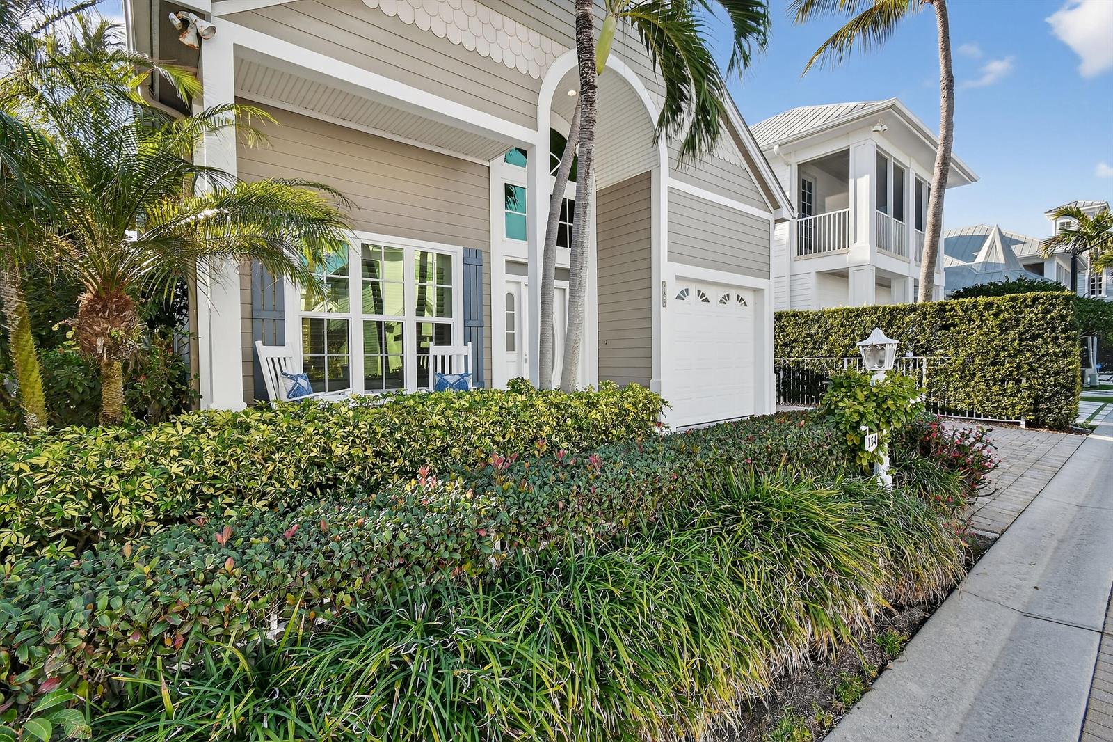 A two-story house with beige siding, a white garage door, and a landscaped front yard — 154 Jupiter Key Road, Jupiter FL 33477, JUPITER, FL