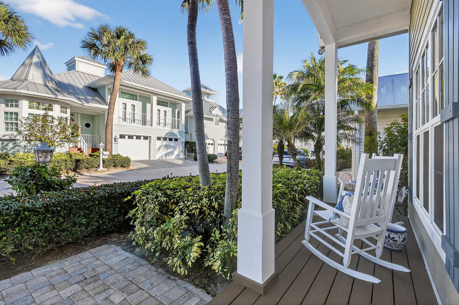A white rocking chair sits on a covered porch overlooking a street with palm trees — 154 Jupiter Key Road, Jupiter FL 33477, JUPITER, FL
