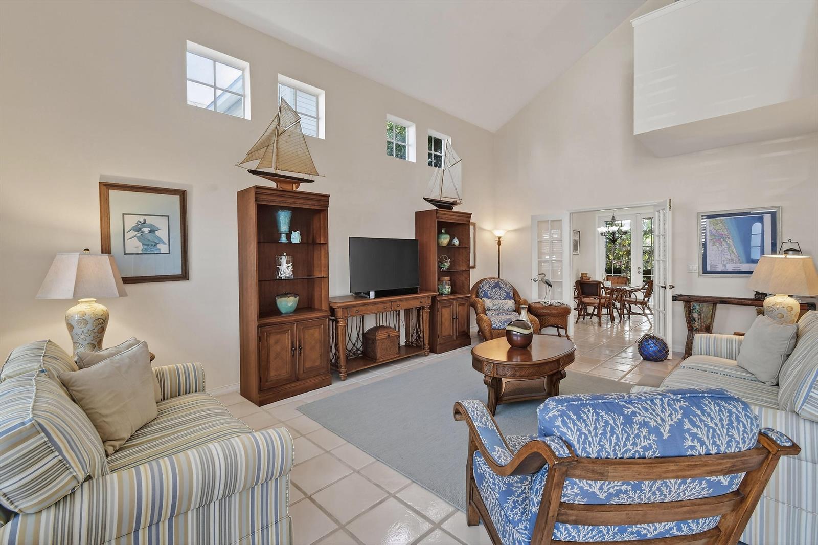 A living room with high ceilings, tile floors, coastal decor, and a television media center — 154 Jupiter Key Road, Jupiter FL 33477, JUPITER, FL