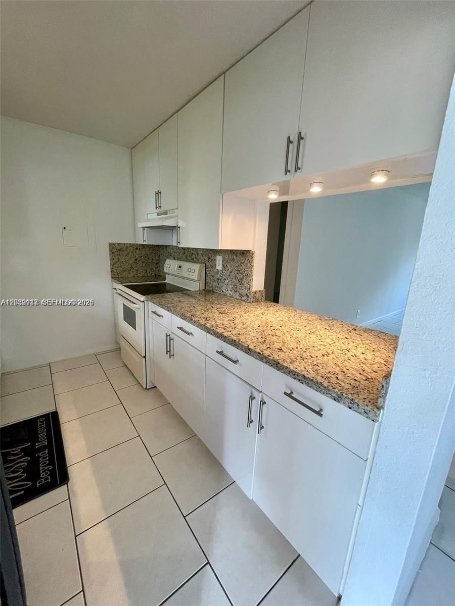 A kitchen features white cabinets, granite countertops, and light-colored tile flooring — 183 Lakeview Dr # 103, Weston FL 33326, WESTON, FL