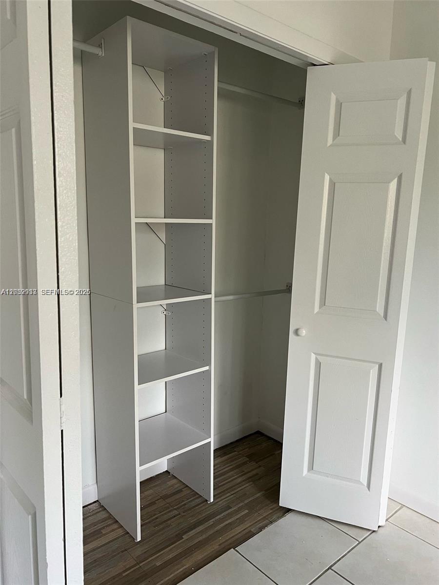A white shelving unit stands inside a closet with a hanging rod and wood-look flooring — 183 Lakeview Dr # 103, Weston FL 33326, WESTON, FL