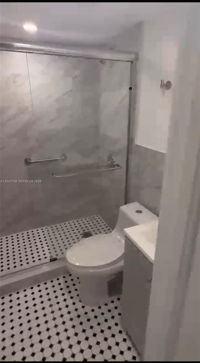 A bathroom features a walk-in shower with marble-look tiles and a black-and-white patterned floor — 1895 SW 22nd # 7, Miami FL 33145, MIAMI, FL
