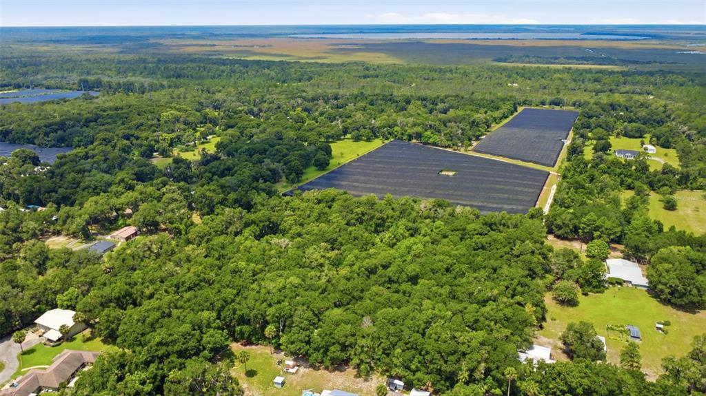 An aerial view shows a large rural property featuring two expansive, black-covered agricultural shade structures — GRAND AVENUE, DELAND, FL