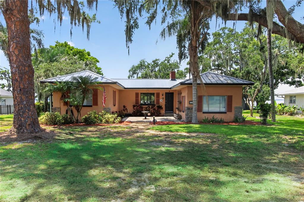 A single-story house with a metal roof, stucco exterior, and a front patio — 32805 LAKE EUSTIS DRIVE, TAVARES, FL