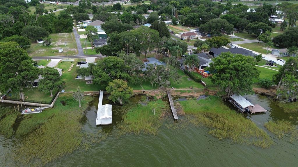 An aerial view shows waterfront homes with private docks and grassy yards along a lake — 32805 LAKE EUSTIS DRIVE, TAVARES, FL