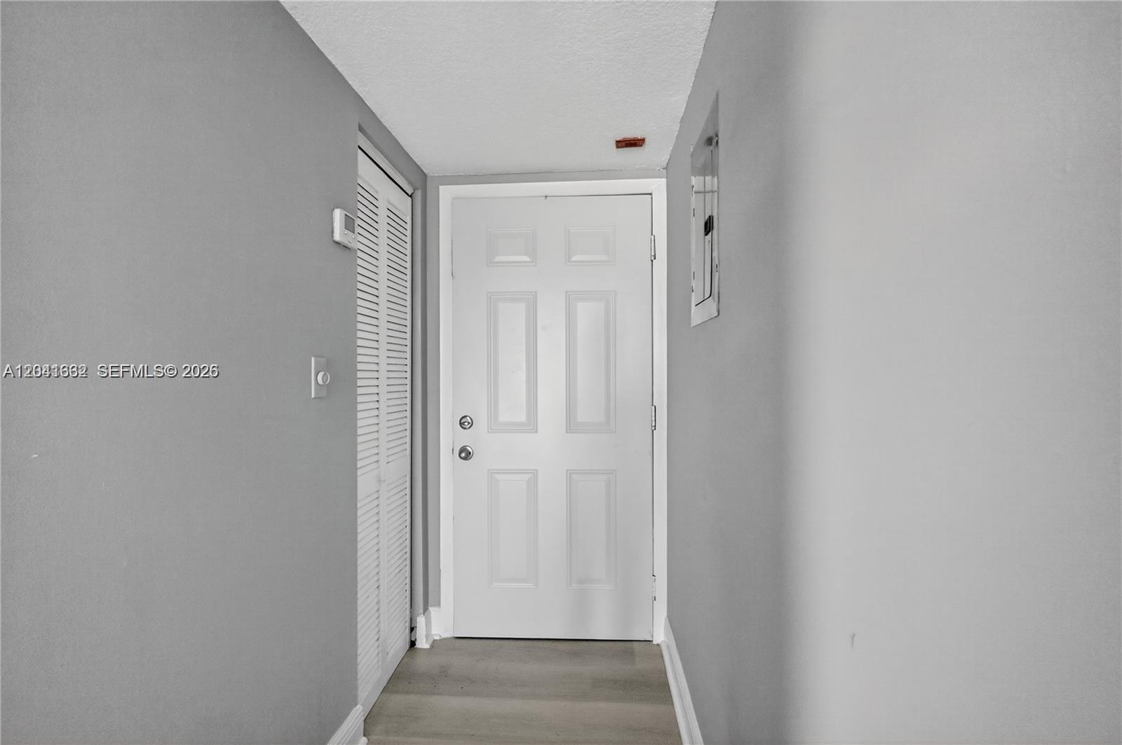 A narrow hallway features gray walls, light wood-look flooring, and a white entry door — HIALEAH GARDENS, FL