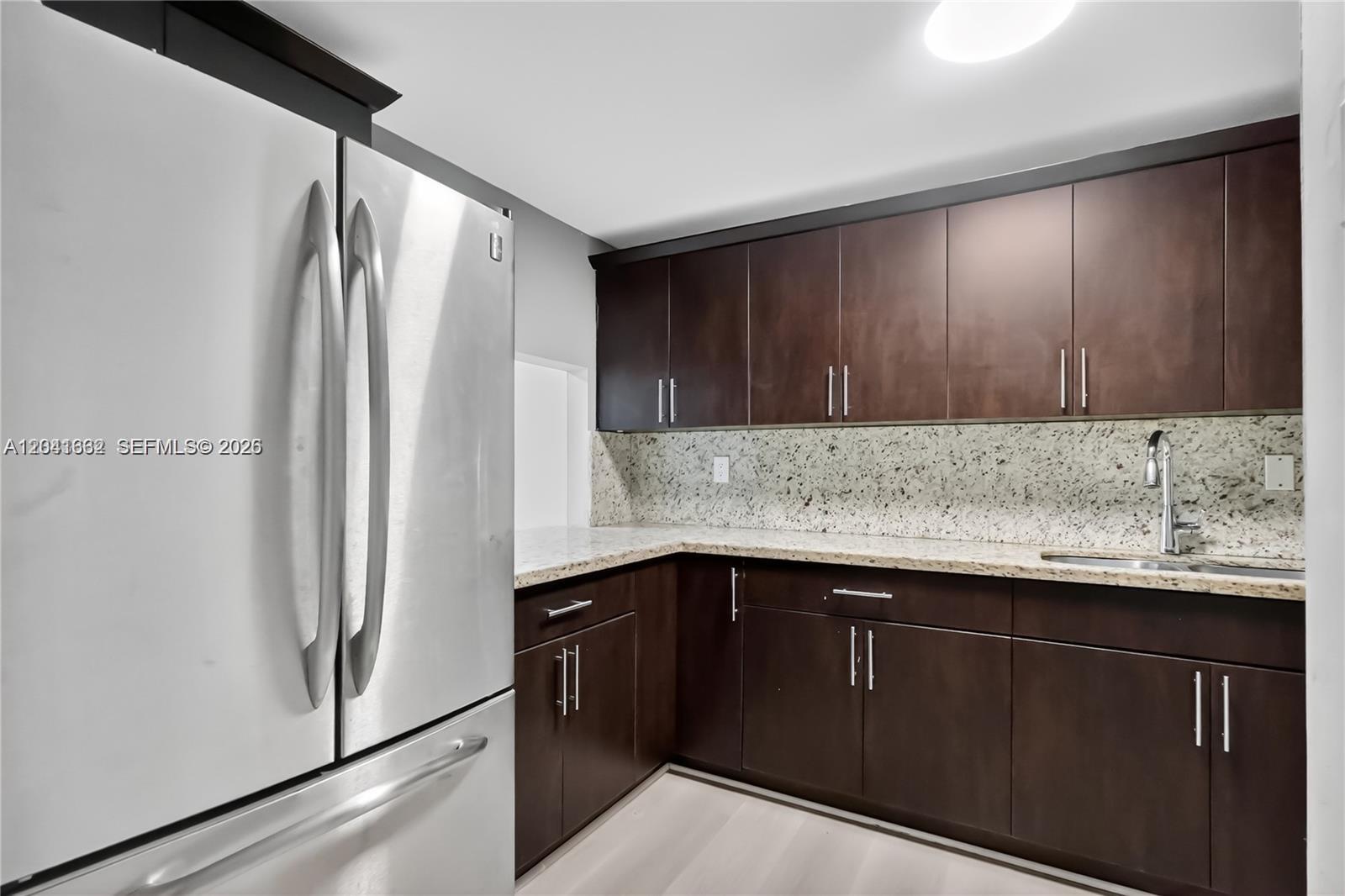 A kitchen features dark wood cabinets, granite countertops, and stainless steel appliances — HIALEAH GARDENS, FL