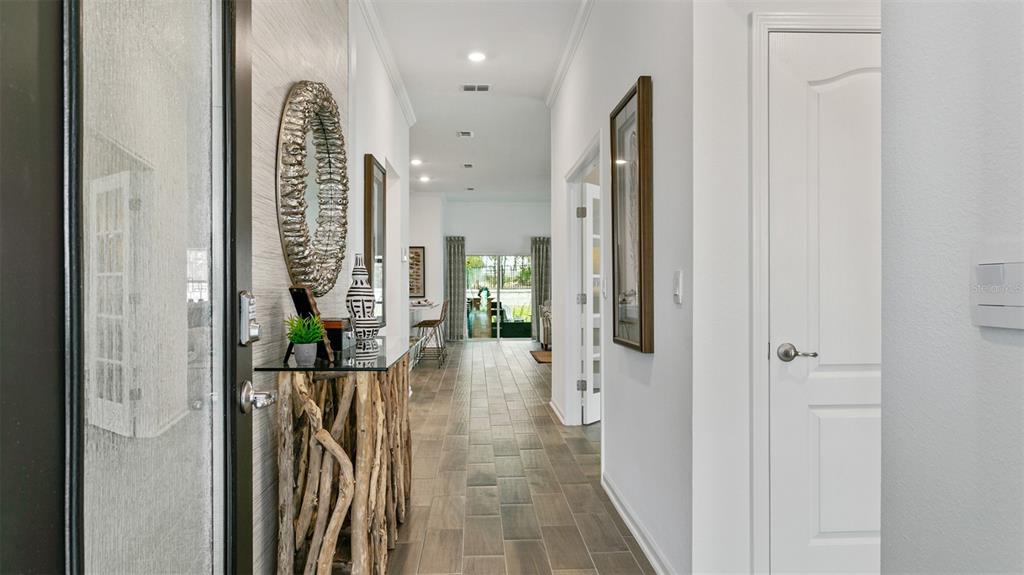 A bright hallway with tile flooring leads from an entryway toward a rear glass door — 141 GREENWOOD DRIVE, PALM COAST, FL