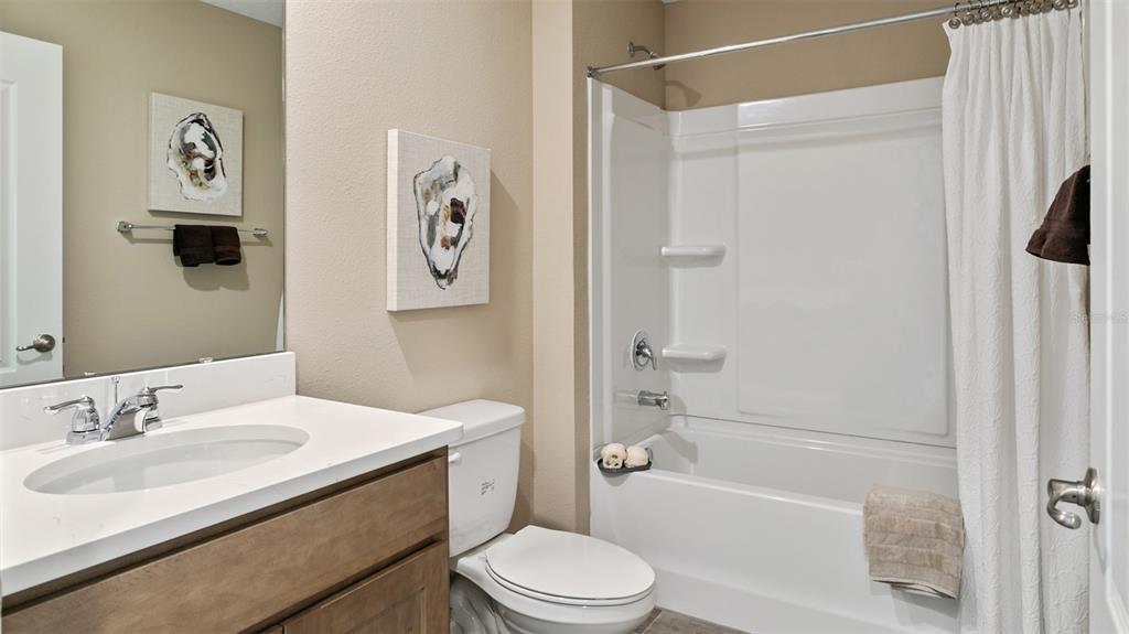 A bathroom features a wood vanity, a white countertop, a toilet, and a tub-shower combo — 141 GREENWOOD DRIVE, PALM COAST, FL
