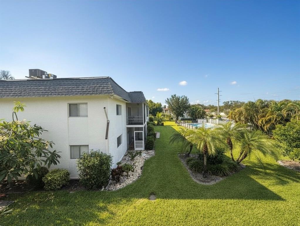 An exterior view of a two-story apartment building next to a grassy lawn and pool — 3606 BENEVA ROAD UNIT 504, SARASOTA, FL