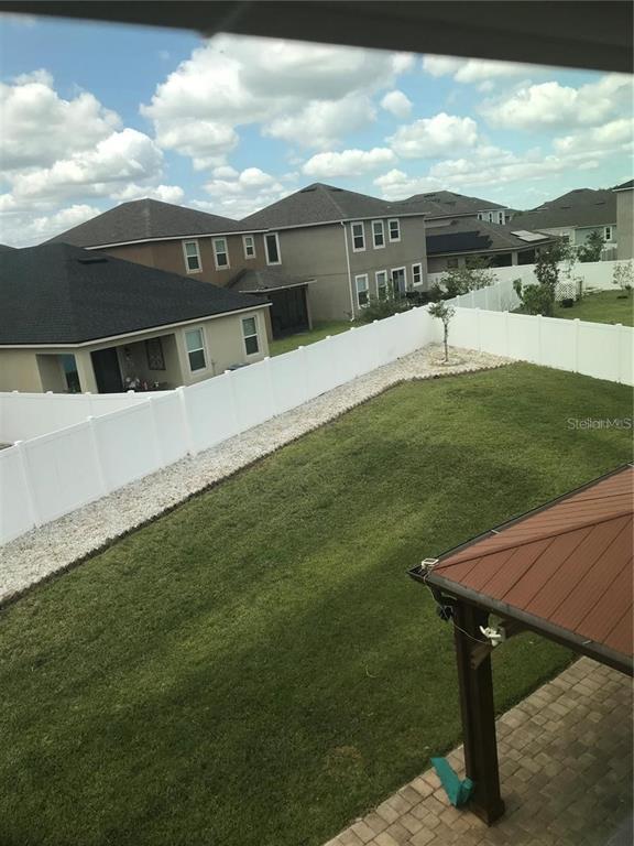 A high-angle view of a fenced backyard with a lawn and a covered patio — 2504 AMATI DRIVE, KISSIMMEE, FL