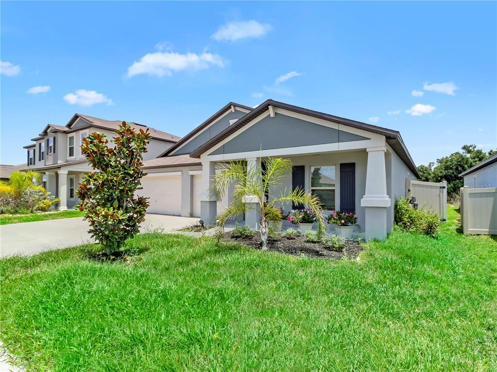 A single-story suburban house with a gray exterior, a front porch, and a manicured lawn — 16568 DELIA STREET, WIMAUMA, FL