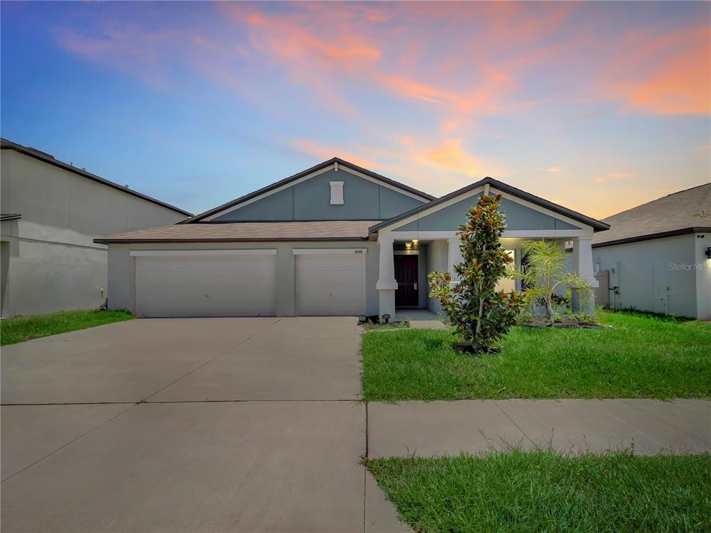 A single-story house with a two-car garage and a covered entryway at sunset — 16568 DELIA STREET, WIMAUMA, FL