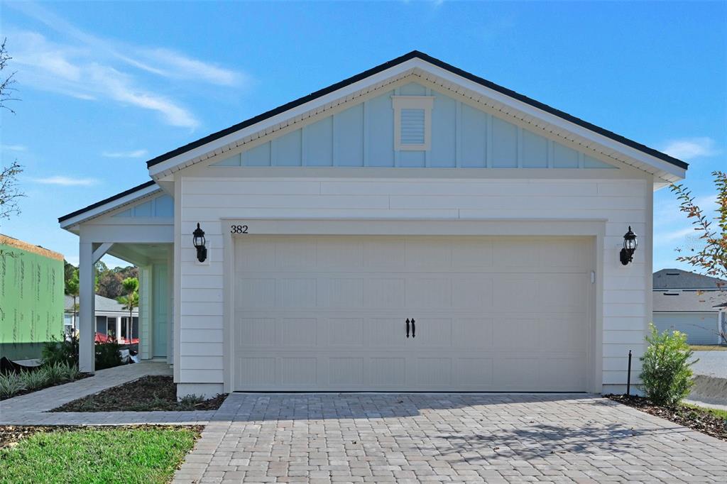 A single-story house exterior features a two-car garage, light siding, and a paved driveway — 343 FISHTAIL PLACE, PALM COAST, FL