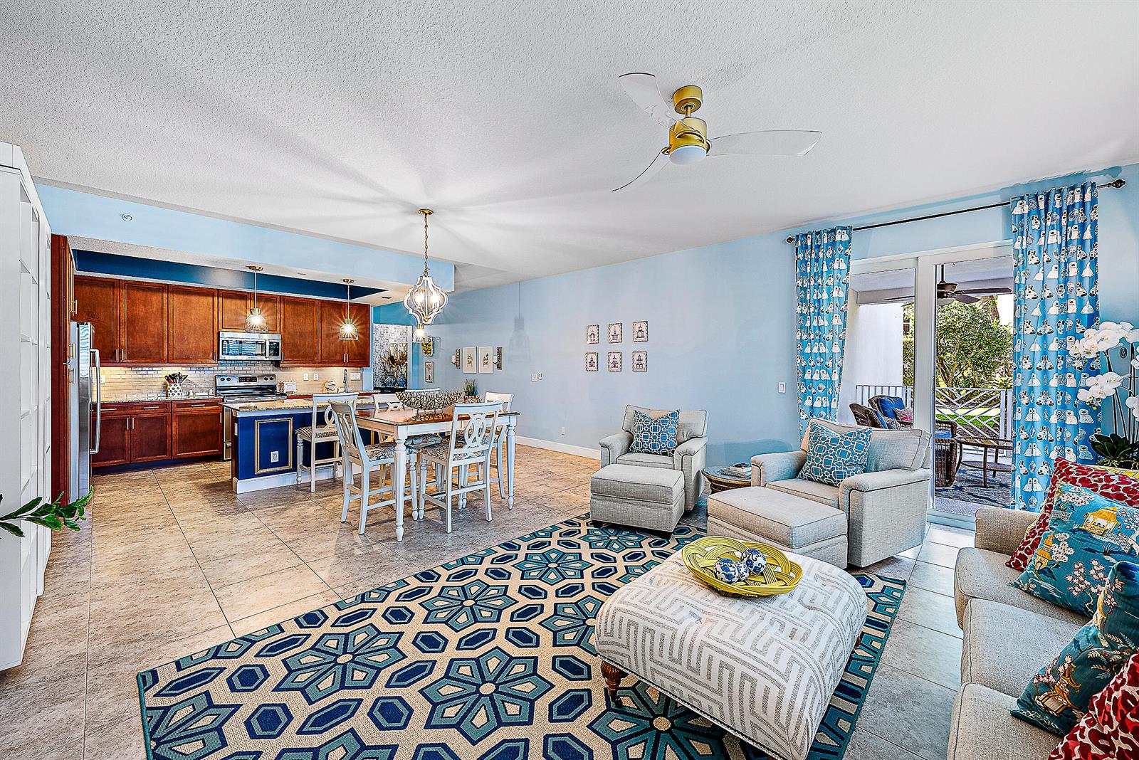 An open-concept living and dining area with light blue walls, tile floors, and wooden cabinetry — 1015 Bay Colony Drive S Slip 17, Juno Beach FL 33408, JUNO BEACH, FL