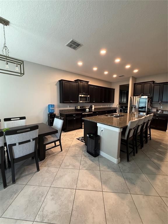 A kitchen features dark wood cabinets, granite countertops, a central island, and an adjacent dining area — 11612 SUNBURST MARBLE ROAD, RIVERVIEW, FL
