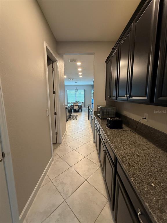 A narrow hallway features dark cabinets, granite countertops, and light-colored diagonal floor tiles — 11612 SUNBURST MARBLE ROAD, RIVERVIEW, FL