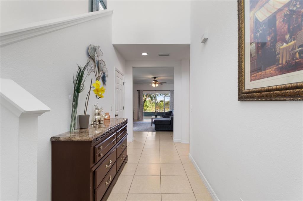 A tiled hallway leads past a wooden dresser toward a living area with sliding doors — 358 ANNABELLE WAY, DAVENPORT, FL