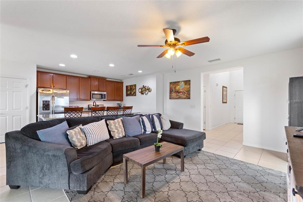 A living room with a large sectional sofa opens to a kitchen with wooden cabinets — 358 ANNABELLE WAY, DAVENPORT, FL
