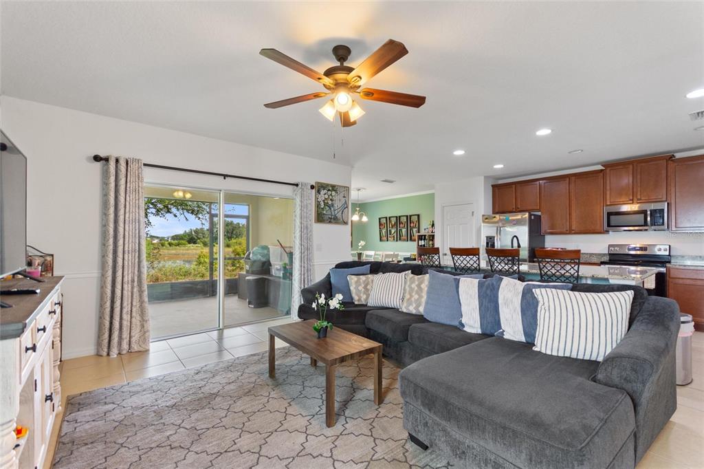 A living room with a sectional sofa, ceiling fan, and sliding doors leading to a patio — 358 ANNABELLE WAY, DAVENPORT, FL