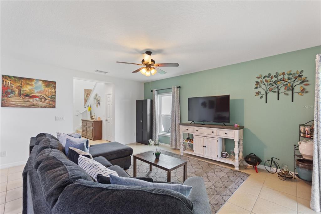 A living room features a dark sectional sofa, a television on a console, and green walls — 358 ANNABELLE WAY, DAVENPORT, FL