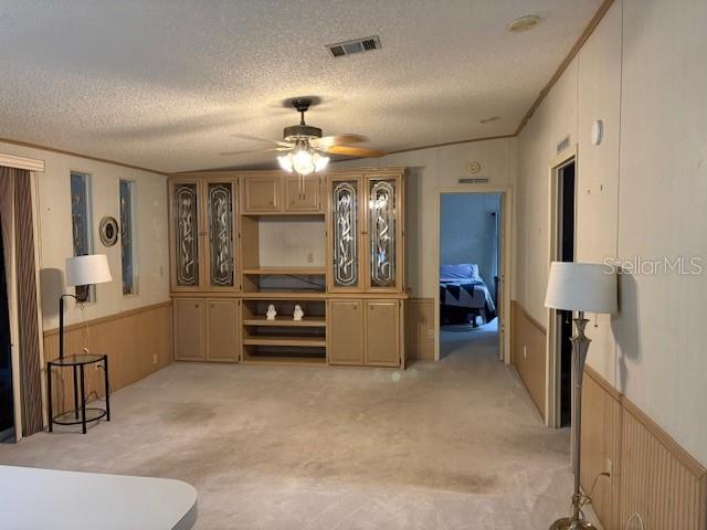 A living room features a large built-in wooden entertainment center, beige carpeting, and two lamps — 4412 TEKA LANE, ST CLOUD, FL