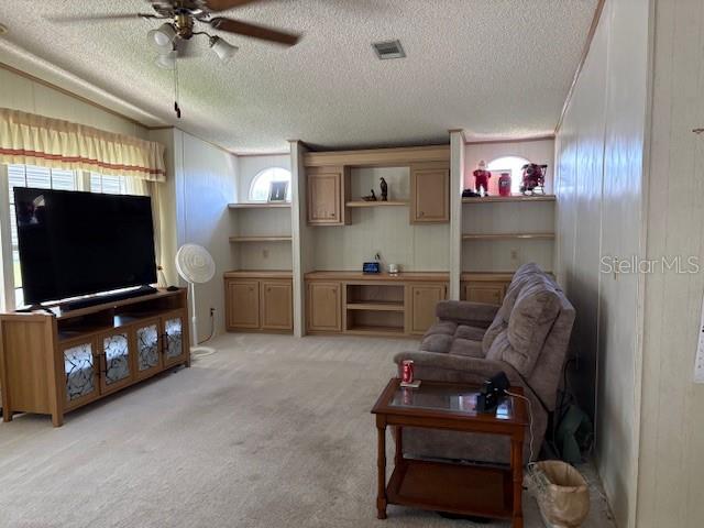 A living room features a large television on a wooden stand, built-in shelving, and carpet — 4412 TEKA LANE, ST CLOUD, FL
