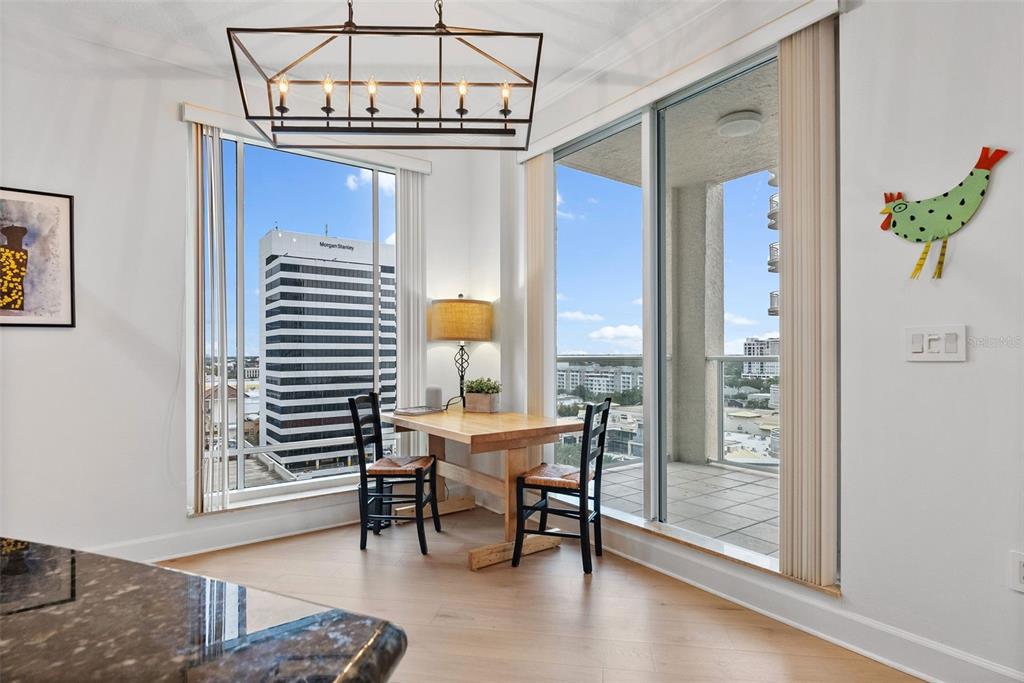 A bright living and dining area with a curved sofa, floor-to-ceiling windows, and water views — 100 BEACH DRIVE NE UNIT 1501, ST PETERSBURG, FL