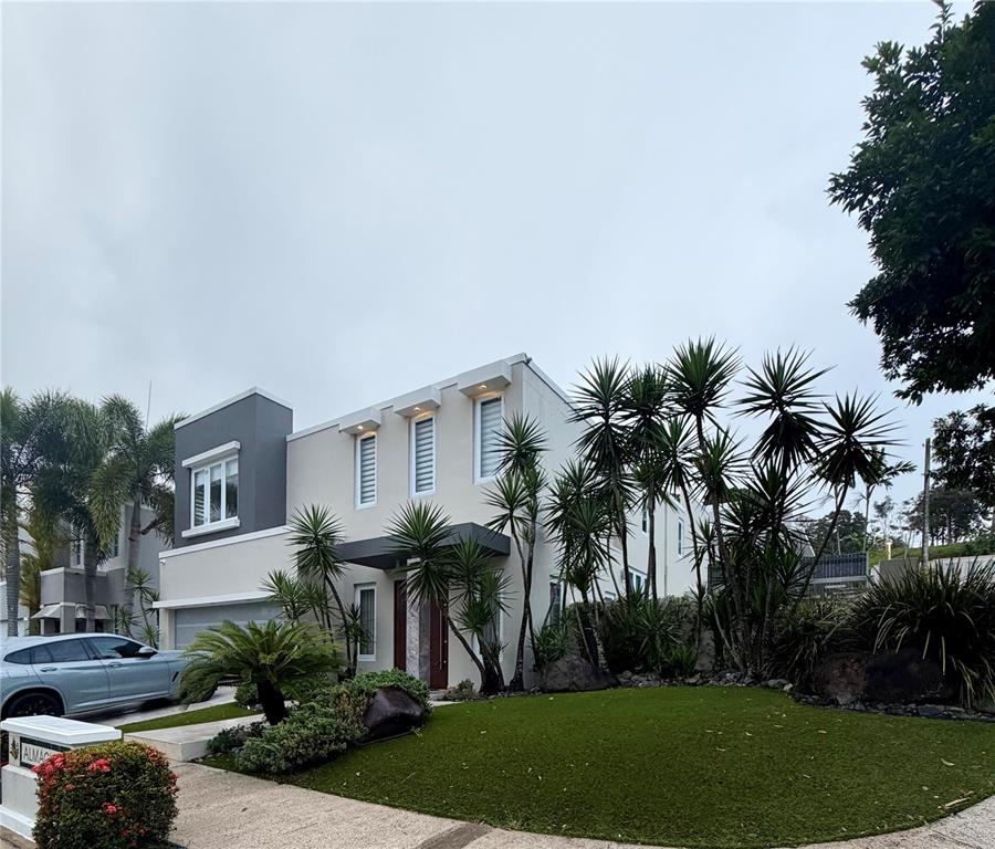 A two-story modern house with a gray and beige exterior sits behind a manicured lawn — 366 LOS ARBOLES DE MONTEHIDRA, SAN JUAN, PR