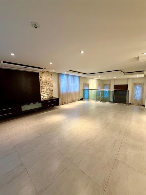 A spacious living room features large floor tiles, a stone accent wall, and glass railings — 366 LOS ARBOLES DE MONTEHIDRA, SAN JUAN, PR